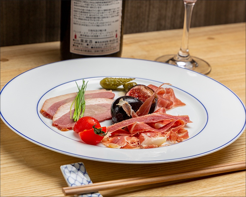 生ハムと鴨肉の盛り合わせと赤ワインの写真